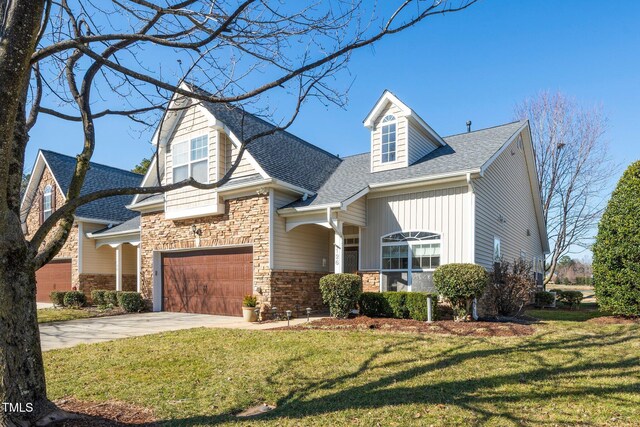 view of front of house with stone siding, roof with shingles, concrete driveway, and a front yard