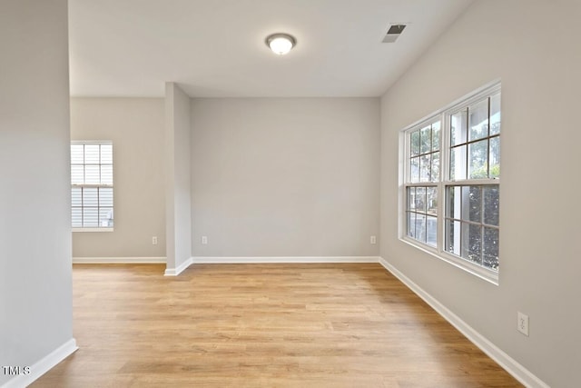 unfurnished room featuring light wood finished floors, visible vents, and baseboards