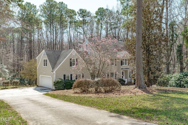 view of front of property with an attached garage, concrete driveway, and roof with shingles