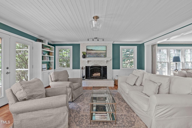 living area with plenty of natural light, a fireplace, a wainscoted wall, and wood finished floors