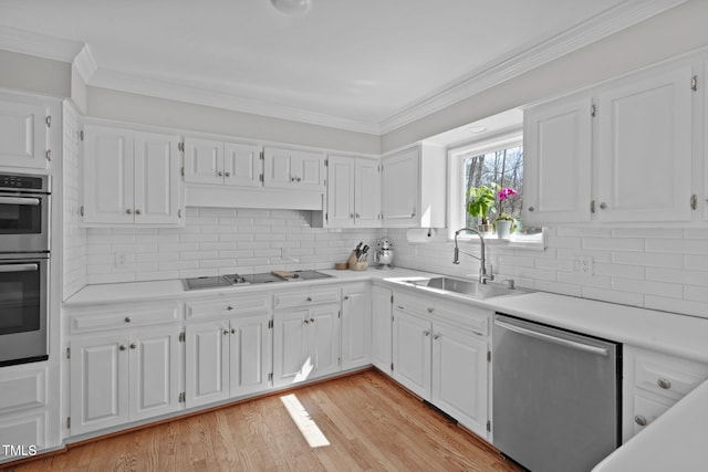 kitchen with a sink, light countertops, appliances with stainless steel finishes, white cabinetry, and light wood-type flooring