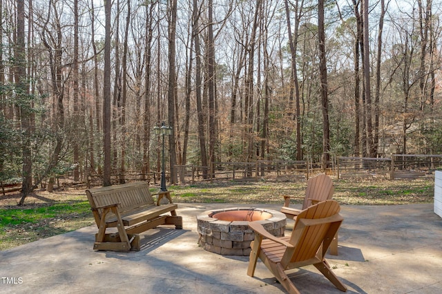 view of patio / terrace with a view of trees, fence, and an outdoor fire pit