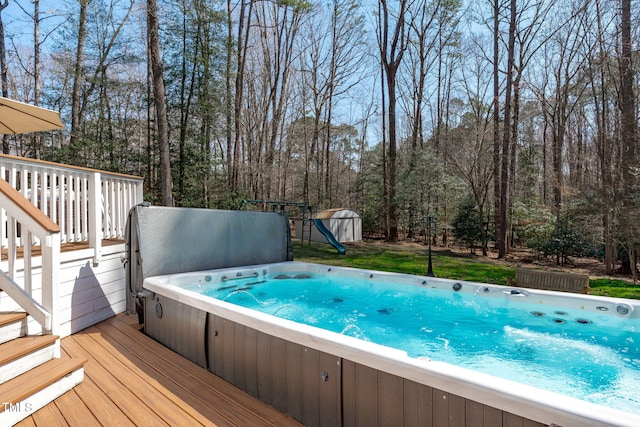 view of pool with a storage shed, a covered hot tub, an outdoor structure, and a wooden deck