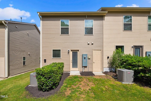 rear view of property featuring central air condition unit and a yard