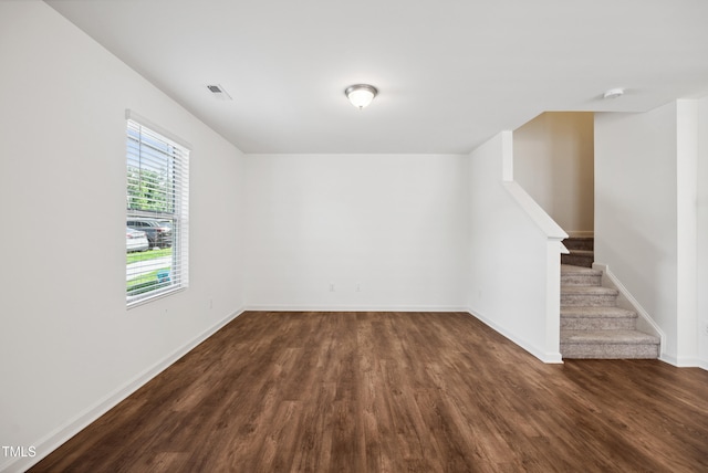 unfurnished room featuring dark wood-type flooring, stairs, baseboards, and a smoke detector