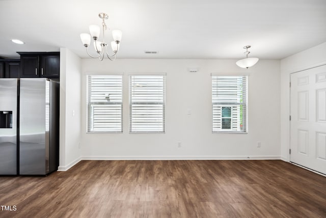 unfurnished dining area with wood finished floors, a chandelier, and baseboards