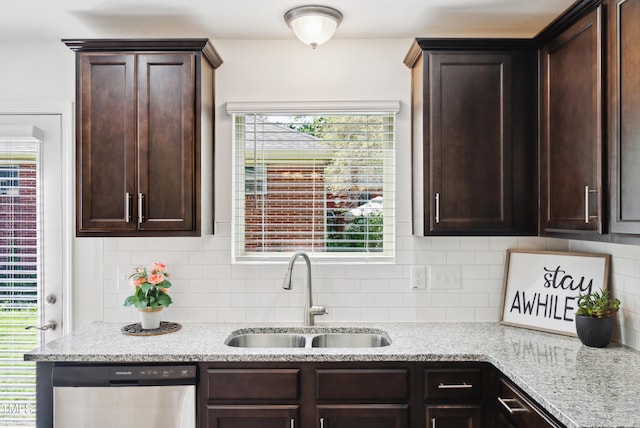 kitchen with stainless steel dishwasher, a sink, dark brown cabinetry, light stone counters, and backsplash