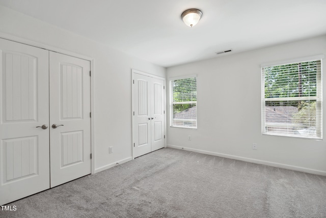 unfurnished bedroom featuring multiple closets, carpet, and baseboards
