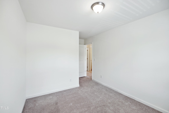 empty room featuring light carpet and baseboards