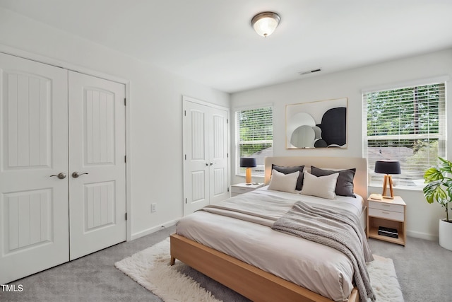 bedroom with two closets, carpet, and baseboards