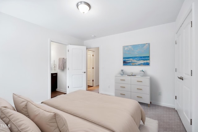 bedroom featuring baseboards, ensuite bathroom, light carpet, and a closet