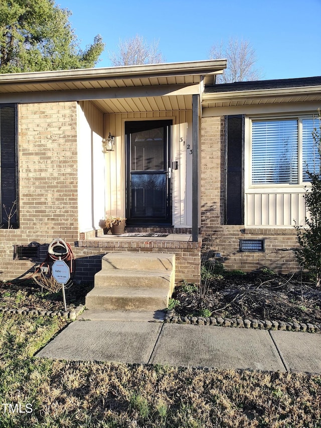 property entrance featuring brick siding, crawl space, and board and batten siding