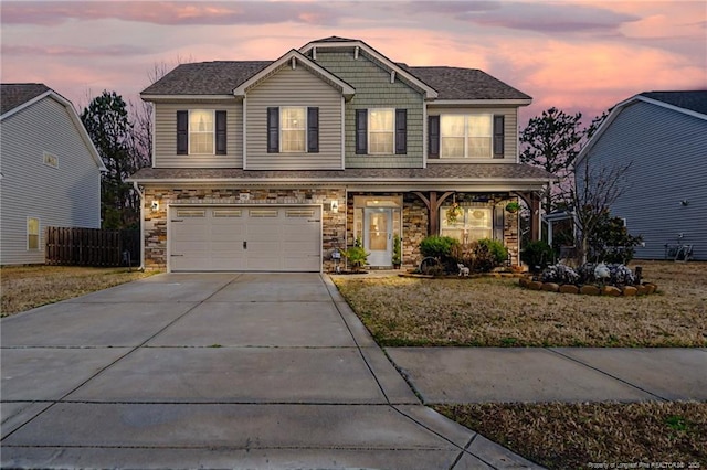 view of front facade featuring stone siding, concrete driveway, fence, and an attached garage