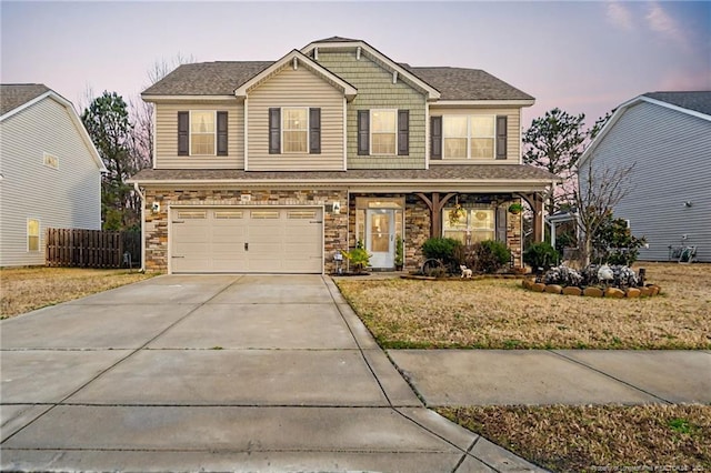 craftsman-style home featuring stone siding, concrete driveway, fence, and an attached garage