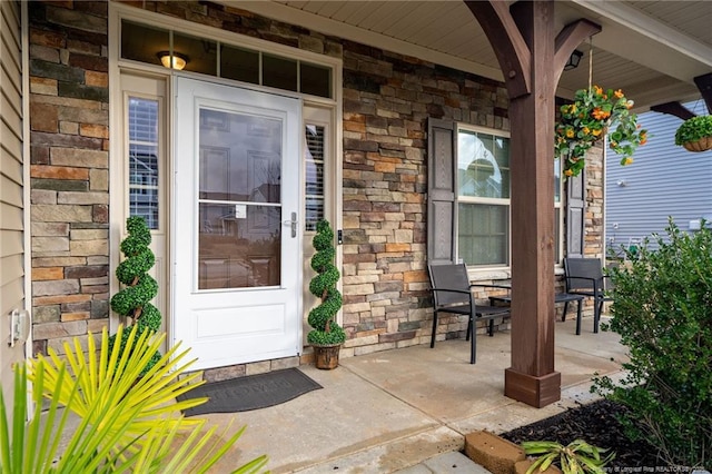 view of exterior entry featuring a porch and stone siding