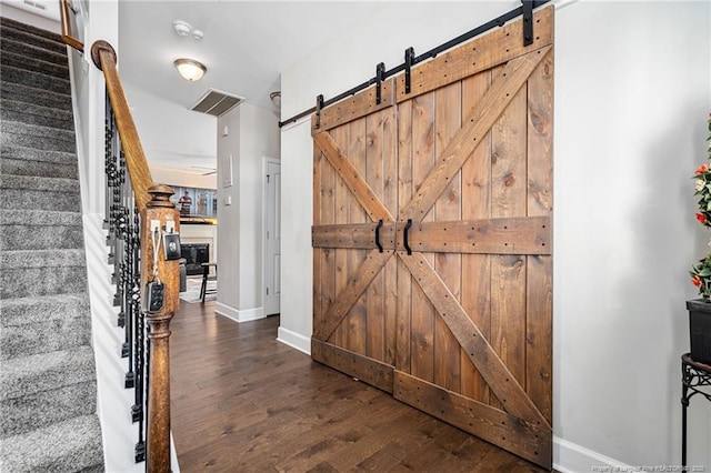 interior space with a barn door, wood finished floors, visible vents, baseboards, and stairs