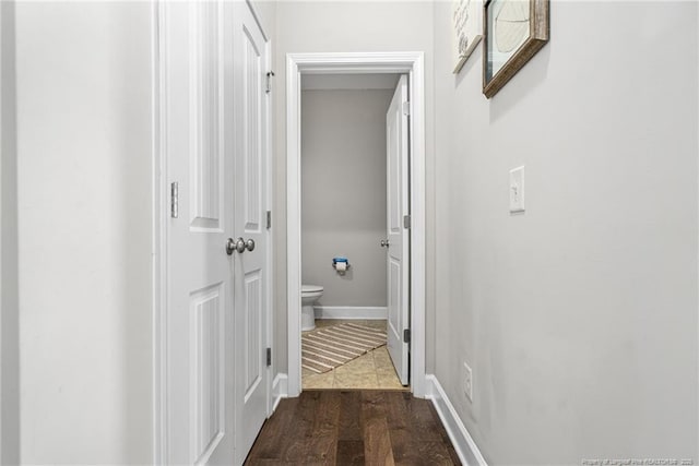 hall with dark wood-type flooring and baseboards