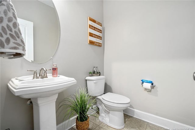 half bathroom featuring baseboards, toilet, and tile patterned floors