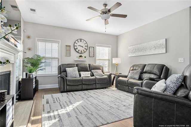 living area featuring ceiling fan, visible vents, wood finished floors, and a high end fireplace