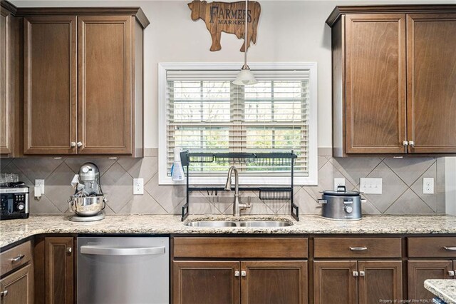 kitchen with dishwasher, light stone counters, a sink, and decorative backsplash