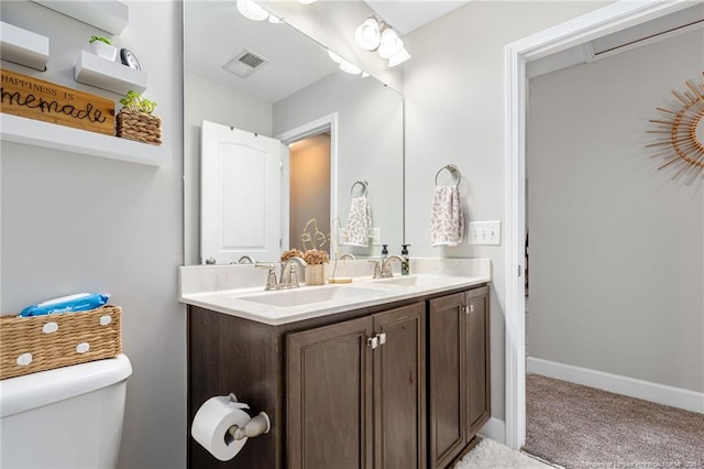 bathroom featuring double vanity, baseboards, visible vents, toilet, and a sink