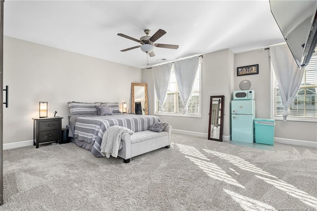 carpeted bedroom with a ceiling fan, multiple windows, and baseboards