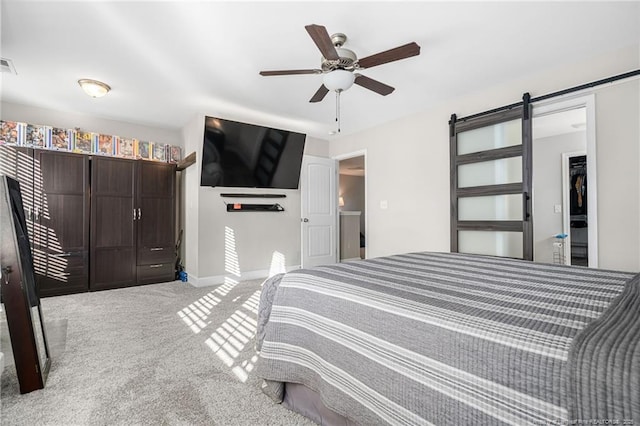 carpeted bedroom featuring visible vents, ceiling fan, and a barn door