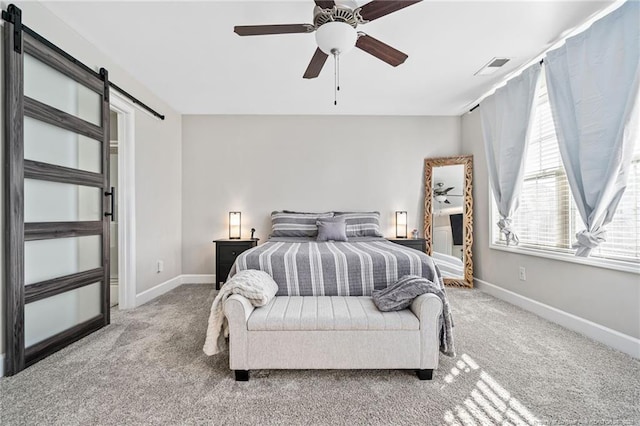 bedroom with carpet floors, a barn door, visible vents, and baseboards