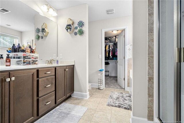 bathroom with visible vents, a spacious closet, vanity, baseboards, and tile patterned floors