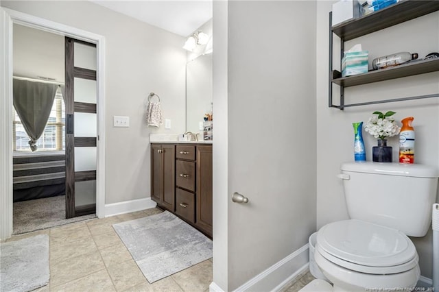 bathroom with toilet, vanity, baseboards, and tile patterned floors