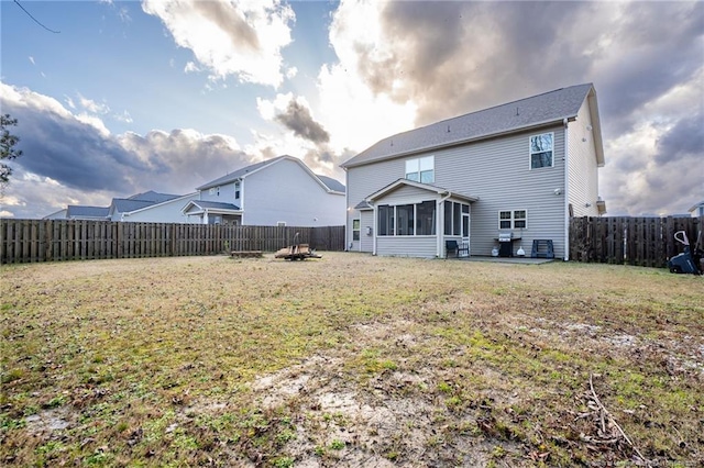 back of house with a sunroom, a fenced backyard, and a yard