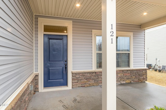 doorway to property featuring stone siding and a porch