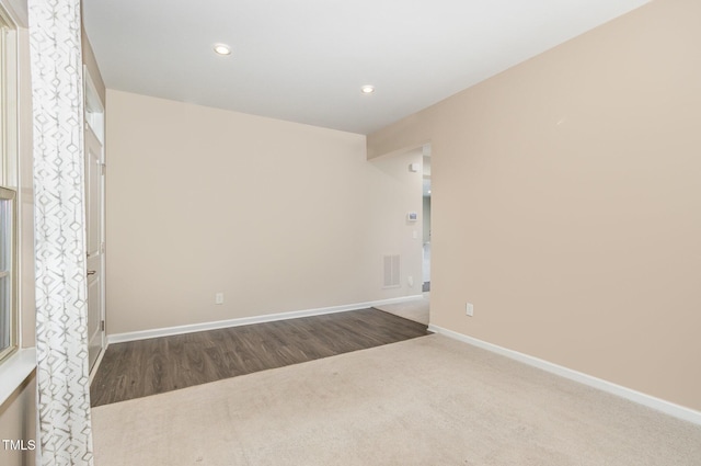 carpeted empty room with wood finished floors, recessed lighting, baseboards, and visible vents