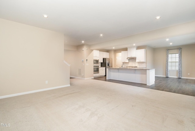 unfurnished living room with visible vents, baseboards, recessed lighting, stairs, and dark carpet