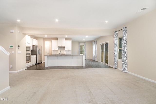 unfurnished living room featuring recessed lighting, baseboards, visible vents, and a sink