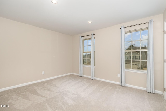 empty room featuring baseboards, a wealth of natural light, and light carpet