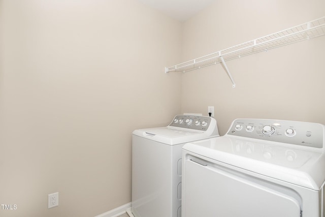 clothes washing area with baseboards, washing machine and dryer, and laundry area