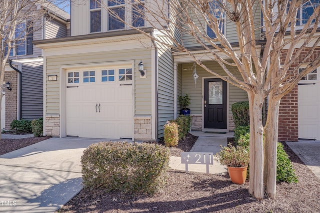 entrance to property with stone siding, concrete driveway, and a garage