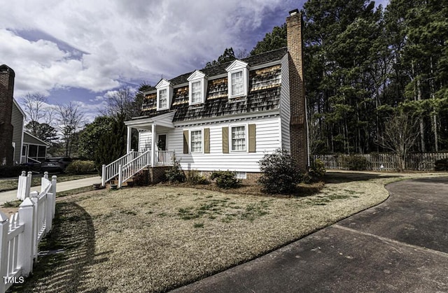 colonial inspired home with a chimney and fence