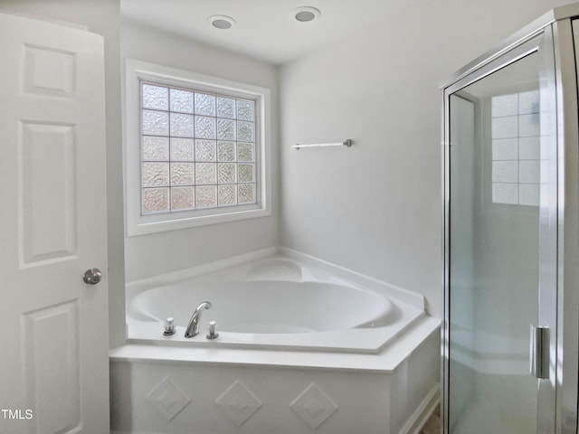 bathroom with a stall shower and a garden tub