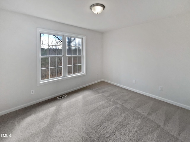 carpeted spare room with visible vents and baseboards