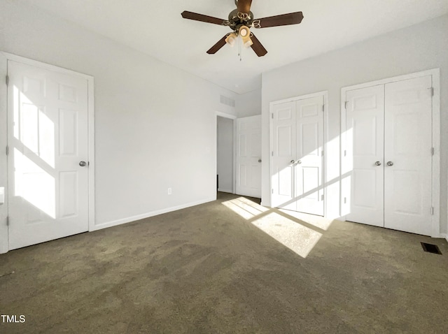 unfurnished bedroom featuring carpet, visible vents, and two closets