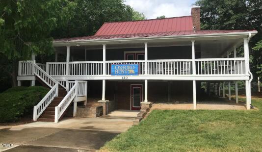 back of property with metal roof, a carport, a chimney, and stairs