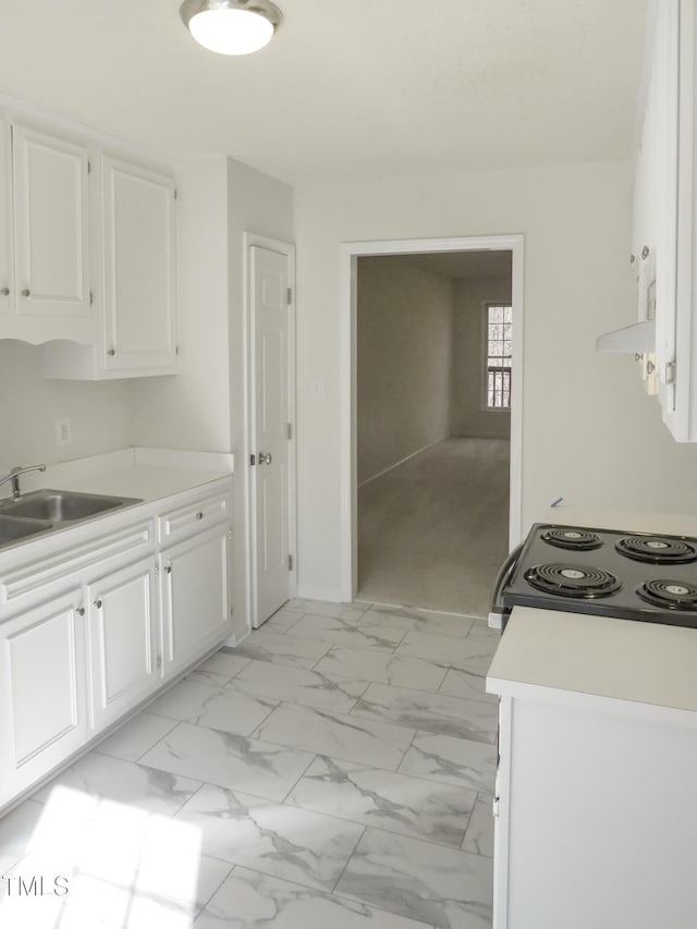 kitchen with light countertops, range with electric stovetop, marble finish floor, white cabinetry, and a sink