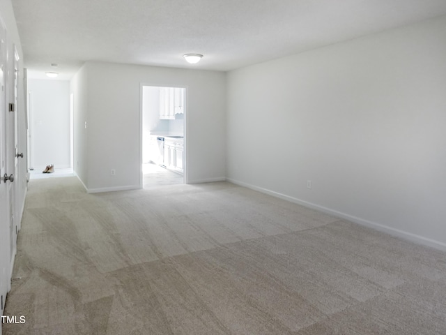 empty room featuring light colored carpet and baseboards