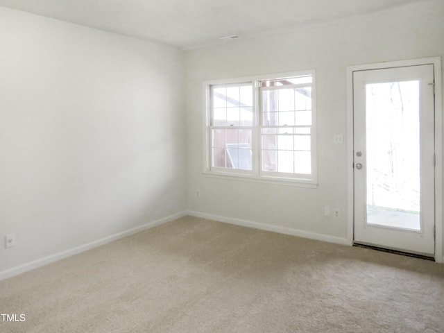 empty room featuring light carpet and baseboards