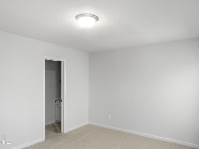 unfurnished bedroom with baseboards, light carpet, and a textured ceiling