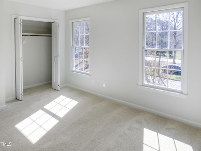 unfurnished bedroom featuring carpet flooring, multiple windows, baseboards, and a closet