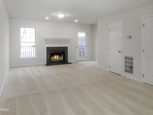 unfurnished living room featuring carpet flooring, recessed lighting, baseboards, and a fireplace with flush hearth