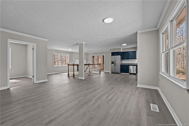 unfurnished living room with dark wood-type flooring, visible vents, crown molding, and baseboards